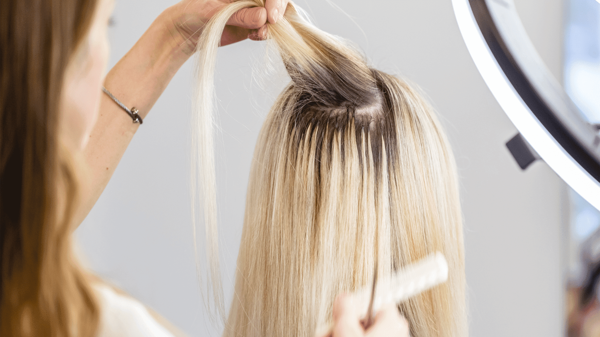 Hairdresser applying blonde highlights to client's hair in a salon setting.