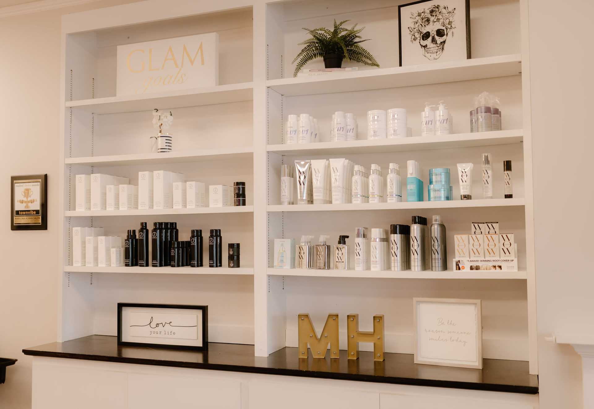Salon shelves with hair and skincare products, decorative signs, and a potted plant.