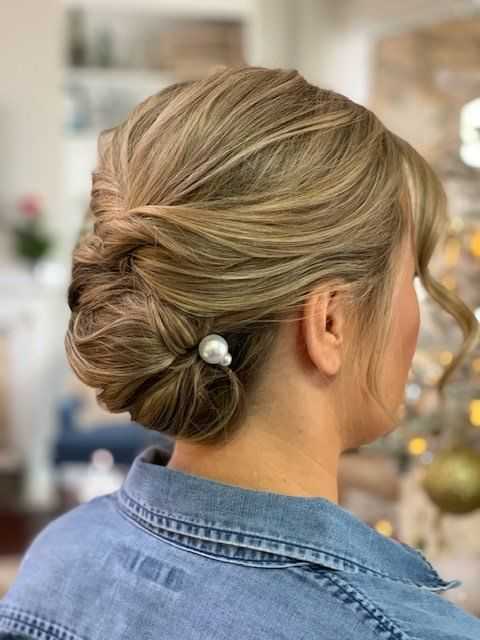 Elegant updo hairstyle with a pearl hairpin, worn by a woman in a denim jacket.